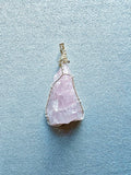 Colgante de cuarzo rosa alargado con vetas naturales, engarzado con hilo de cobre bañado en plata.