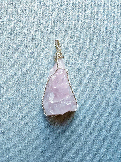 Colgante de cuarzo rosa alargado con vetas naturales, engarzado con hilo de cobre bañado en plata.