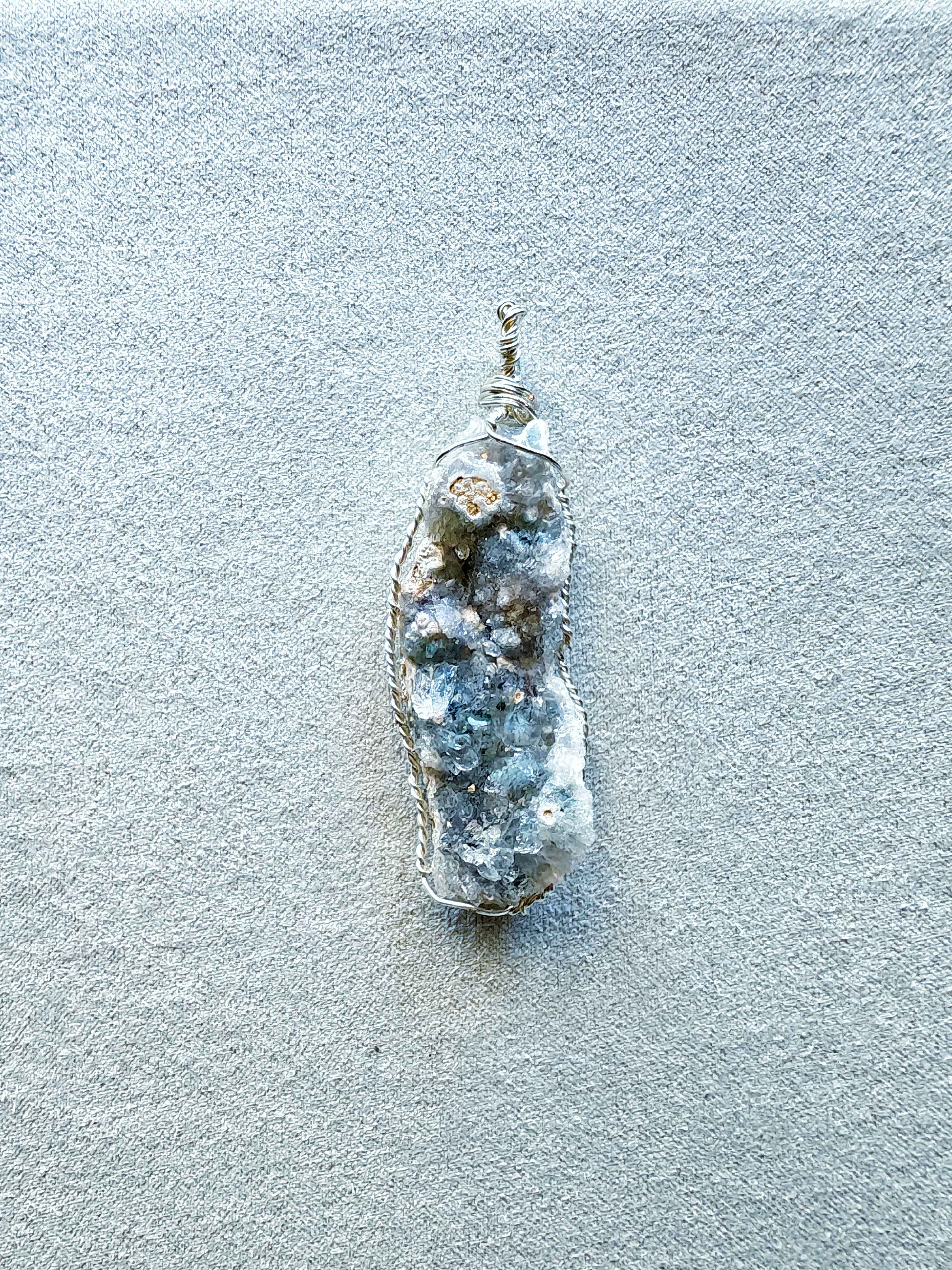 Colgante de drusa de amatista clara en tonos azul-gris engarzada a mano con hilo de cobre bañado en plata, con cordón negro incluido