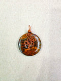 Colgante donut de ojo de tigre natural engarzado a mano en cobre