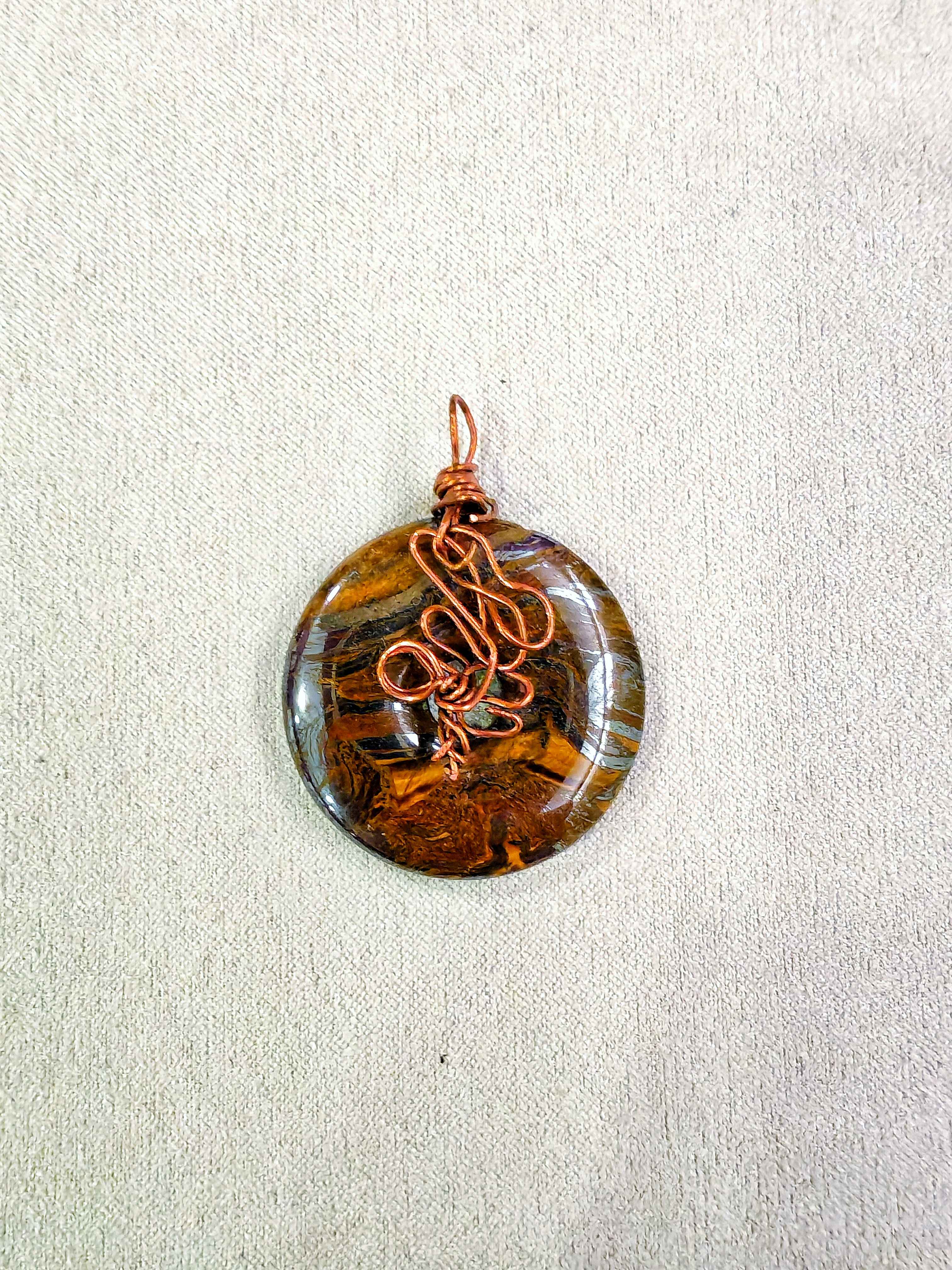 Colgante donut de ojo de tigre natural engarzado a mano en cobre