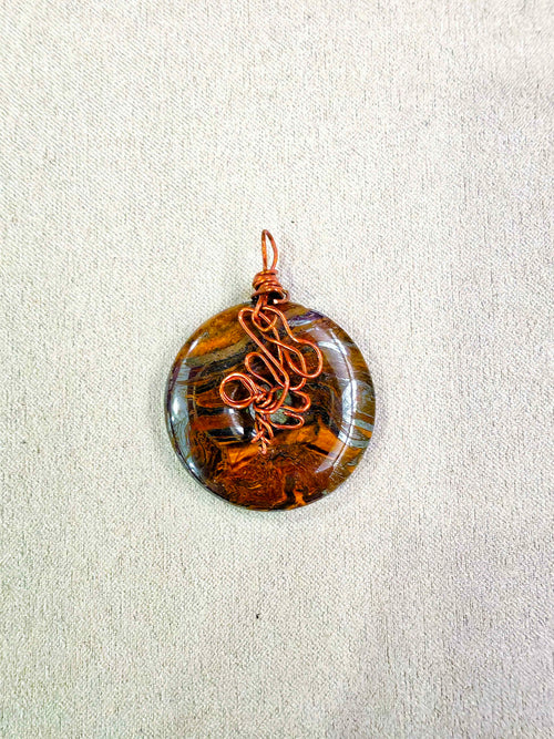 Colgante donut de ojo de tigre natural engarzado a mano en cobre
