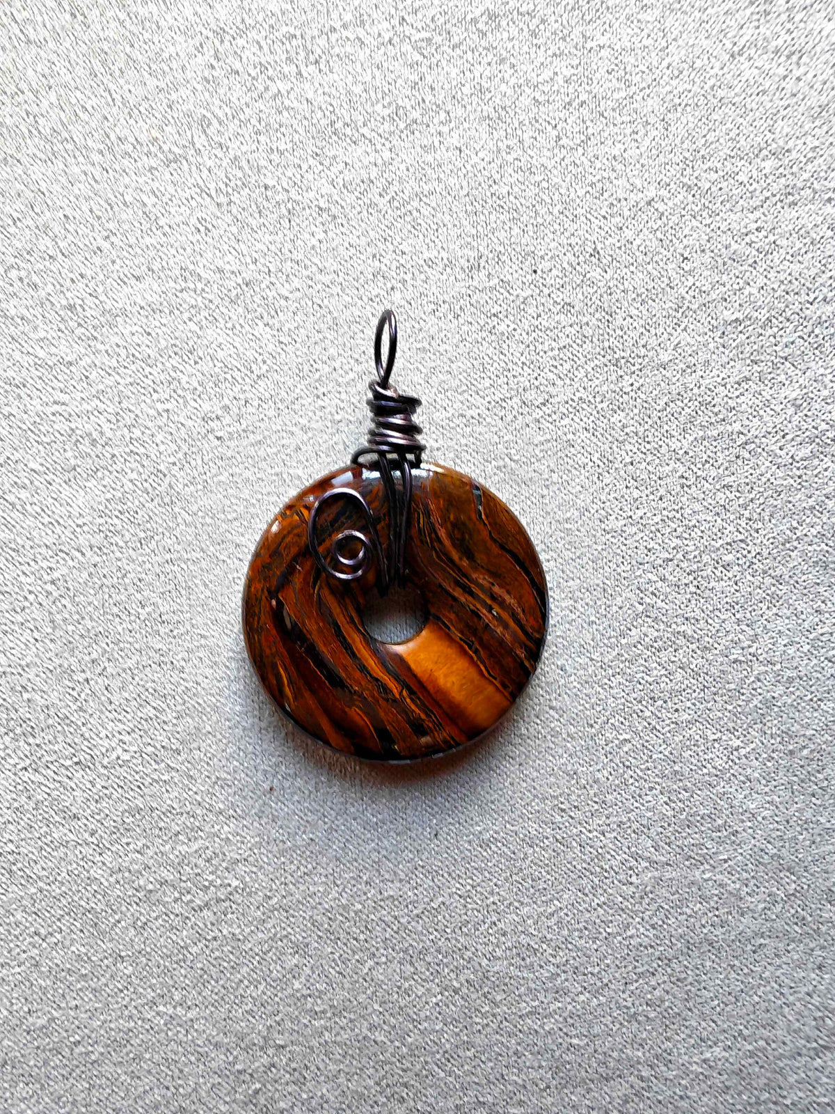 Colgante circular de ojo de tigre con vetas doradas y marrones y engarce de cobre en espiral